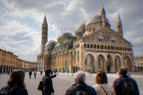 A guide and a small group on a wide paved square before a vast basilica with a row of grey domes and two slender bell towers, Basilica of Saint Anthony