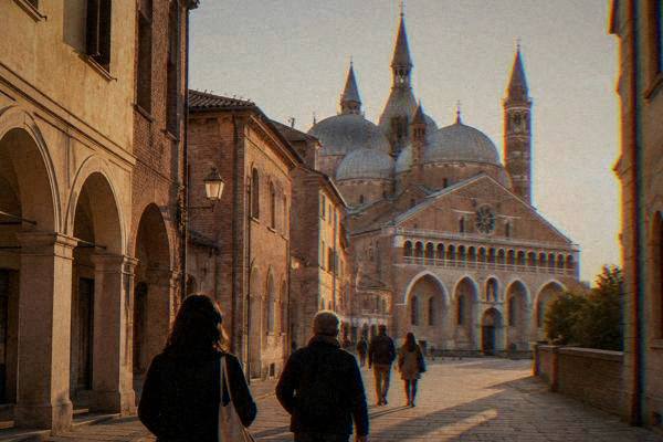 A guide and a few visitors seen from behind walking toward the front of a great domed basilica at the end of a quiet street, Basilica of Saint Anthony