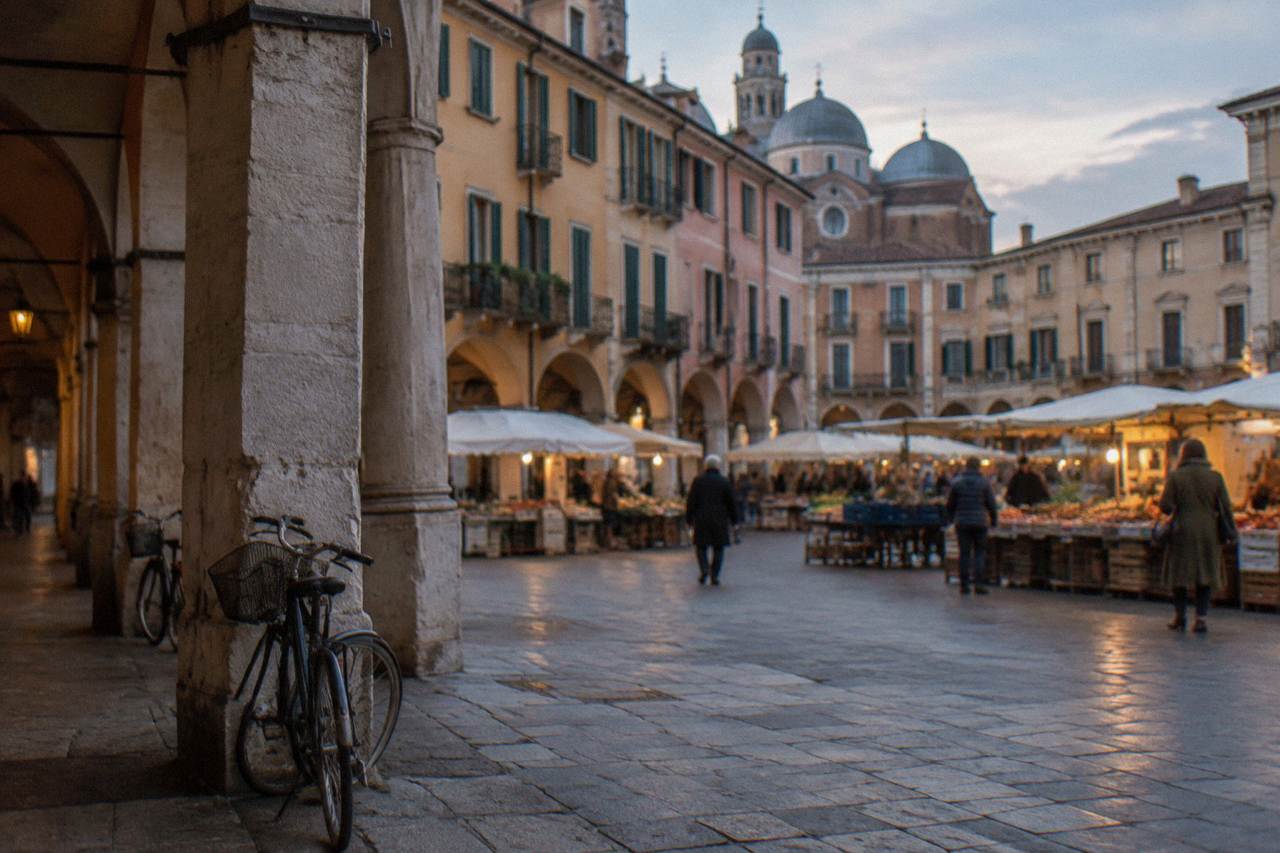 Arcaded square in central Padua with market stalls and historic buildings under soft daylight