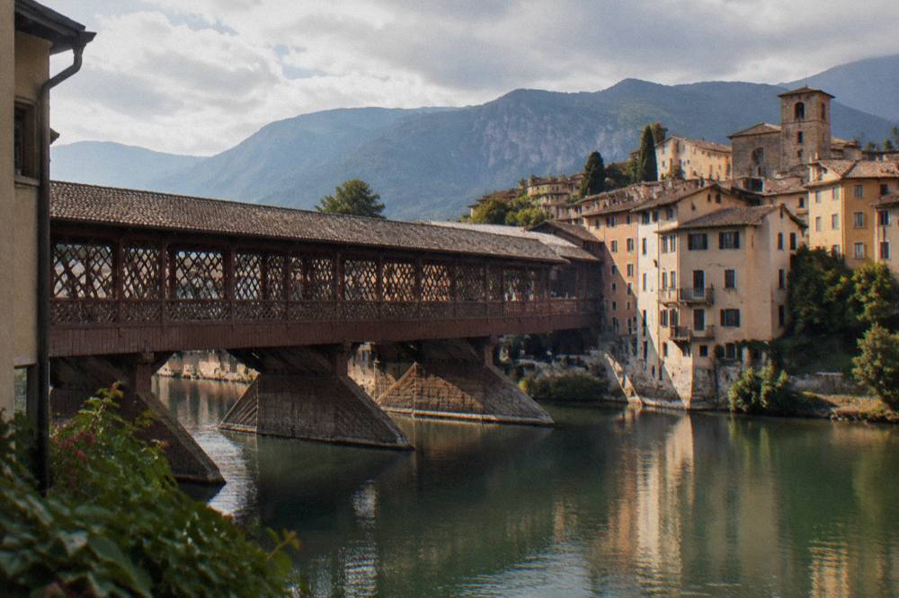 Close view of a covered wooden bridge with lattice windows over calm river water