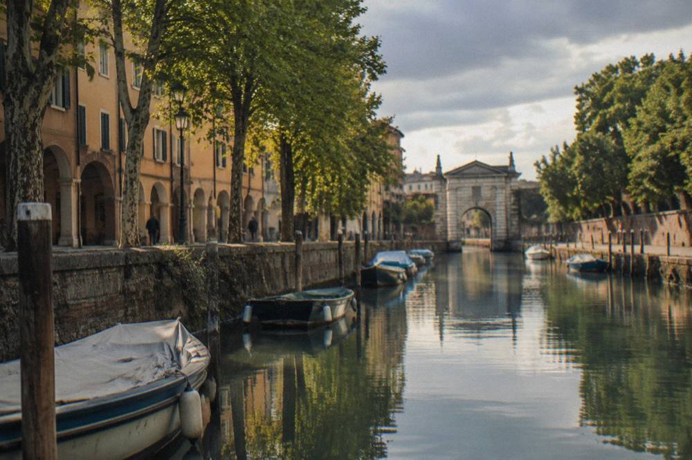 A canal in Padua lined with trees and old walls near the Portello gate