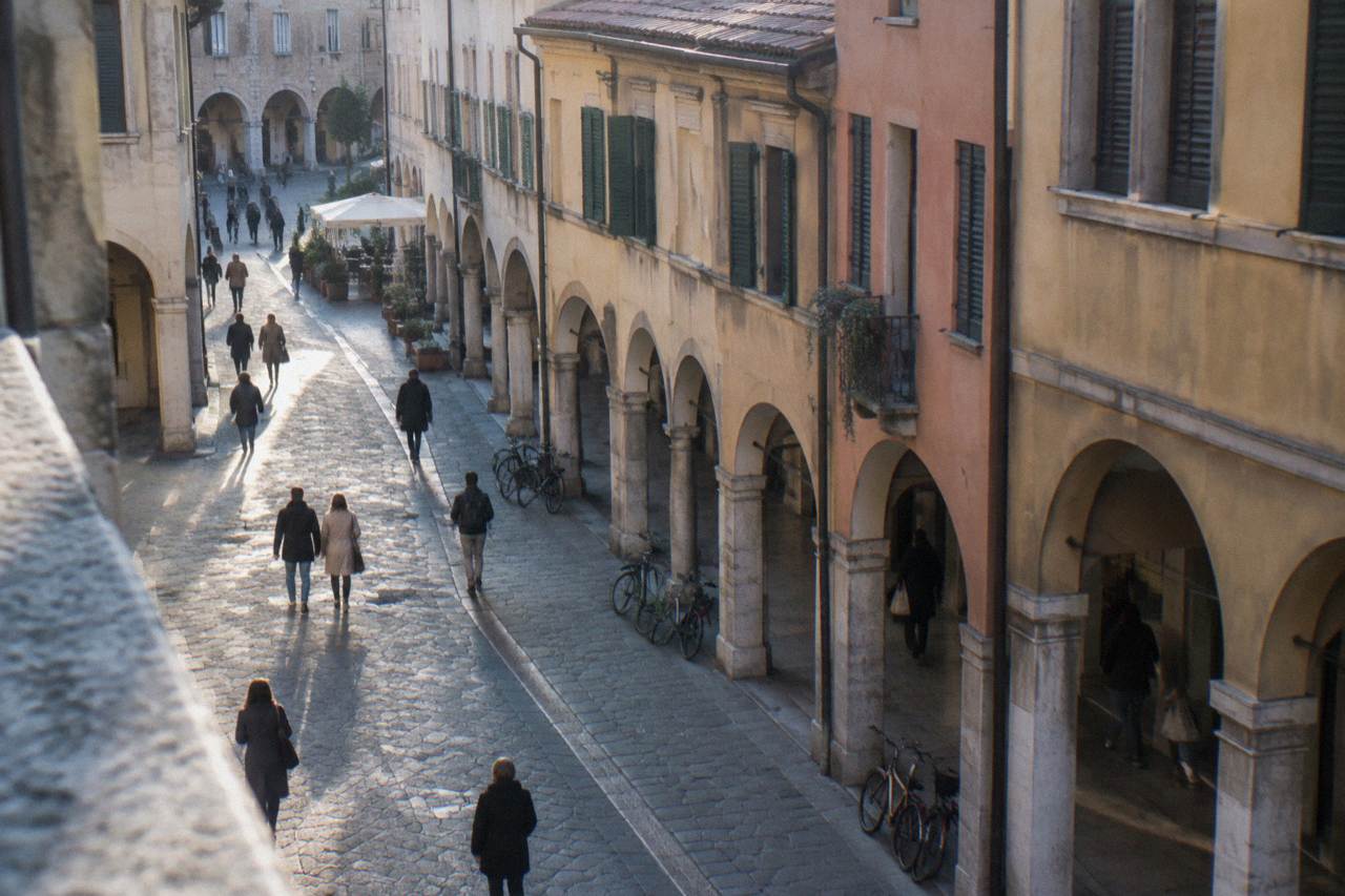 An arcaded street in central Padua with people walking in the early evening