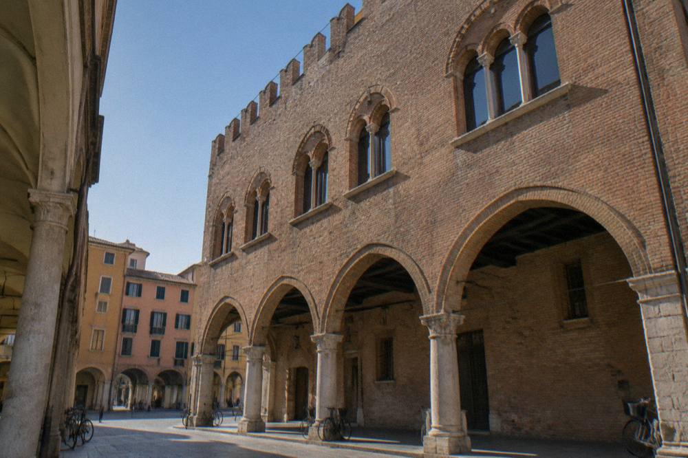 The brick facade and arched windows of a medieval building in Padua under a clear sky