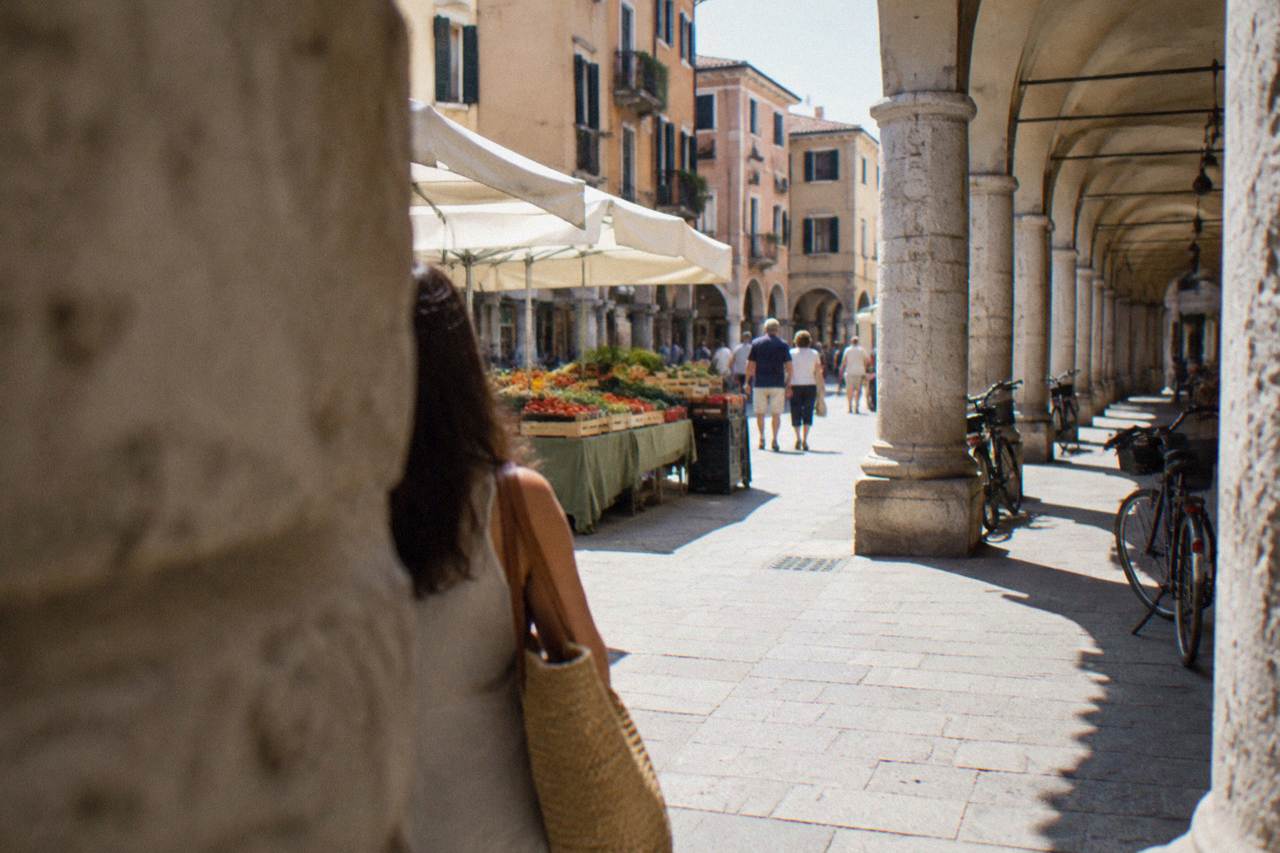 Arcaded street and market stalls in Padua's historic centre on a bright day