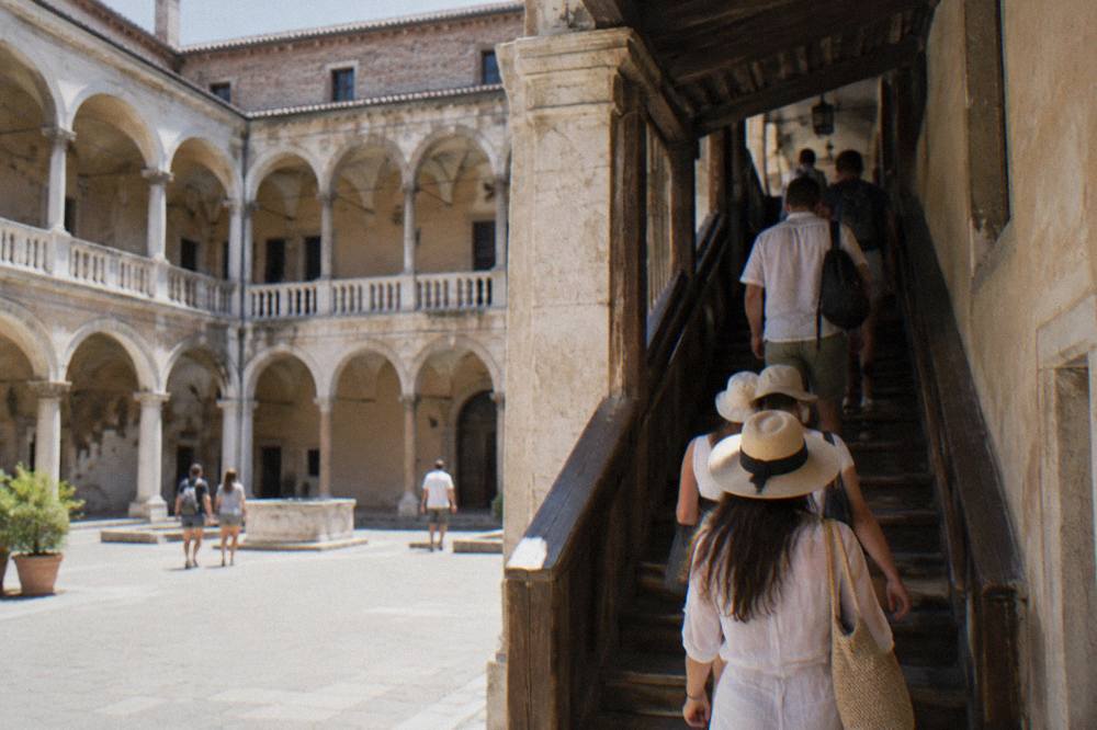 Visitors climbing the narrow wooden stairwell toward the anatomical theatre galleries in Padua
