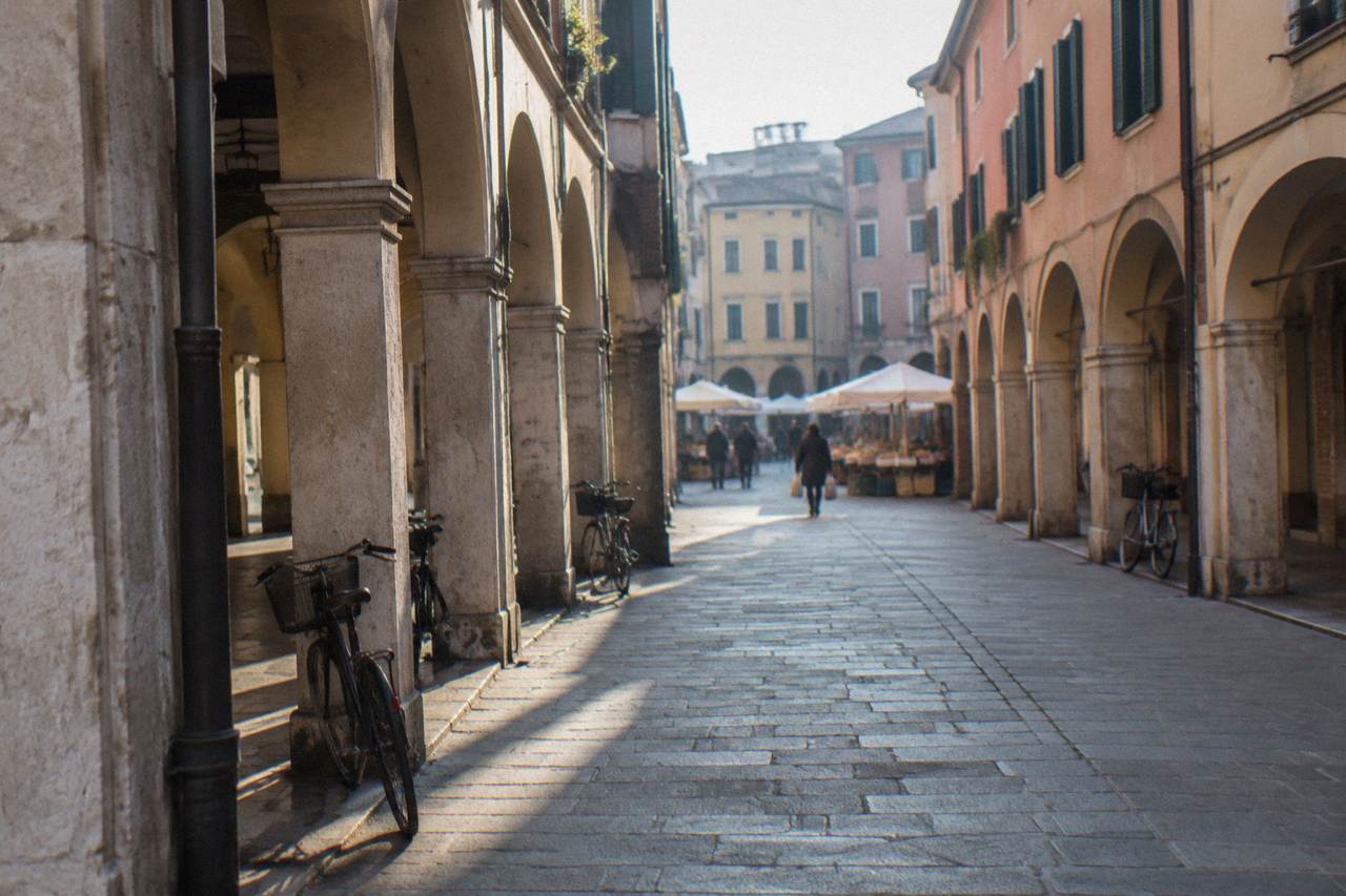 An arcaded street in the centre of Padua with market stalls in the distance