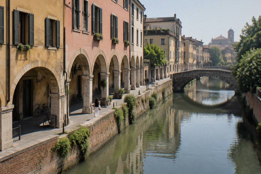 A quiet canal of the Bacchiglione river running past old walls in Padua