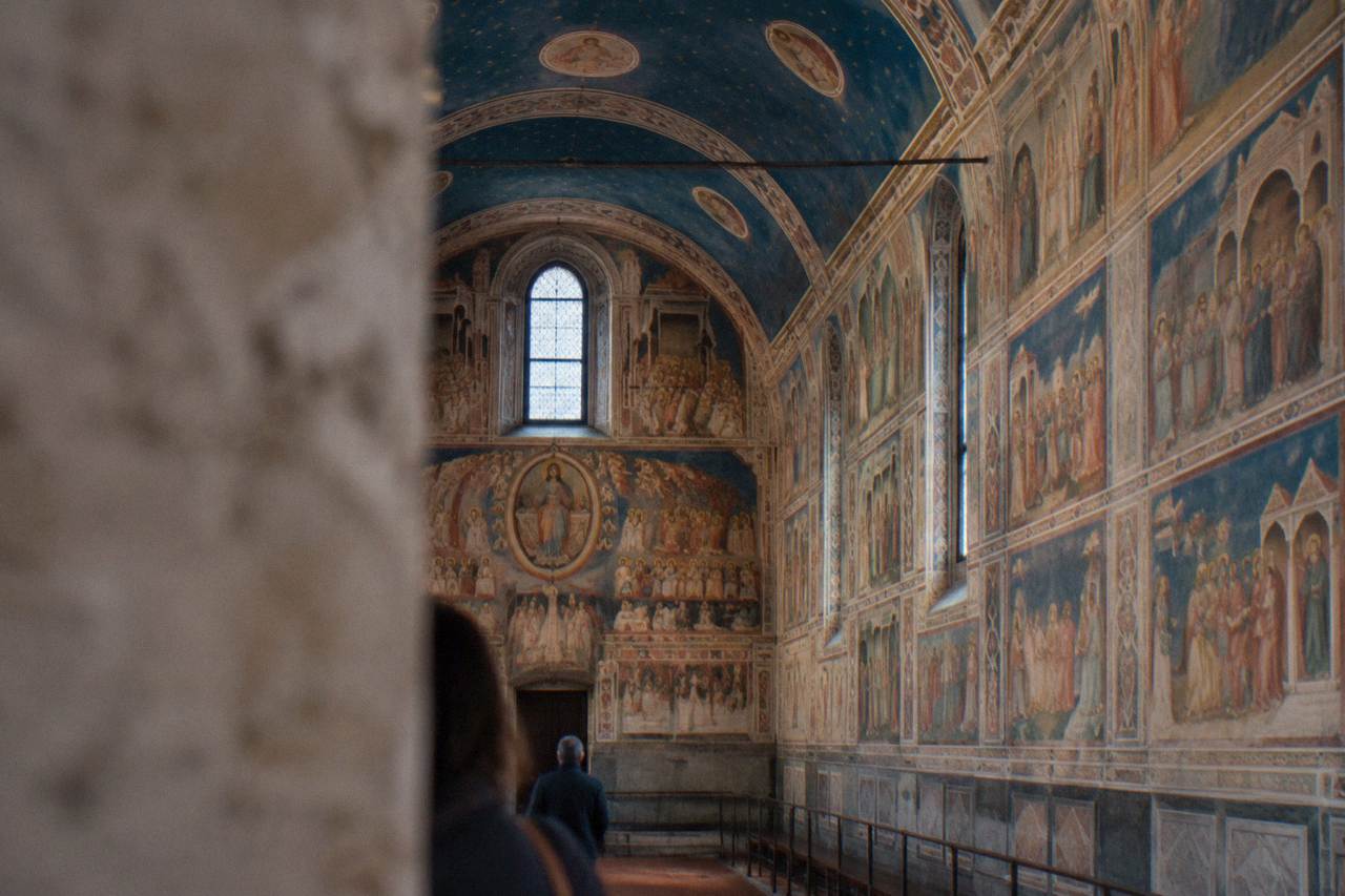 The frescoed interior of the Scrovegni Chapel in Padua, with blue and gold ceiling panels above painted narrative scenes