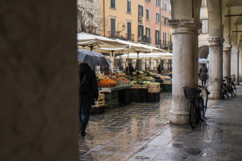 Open-air fruit and vegetable market under the arcades of a Padua square