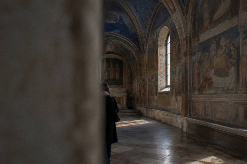 Interior of a frescoed chapel with blue painted vaults and narrative scenes