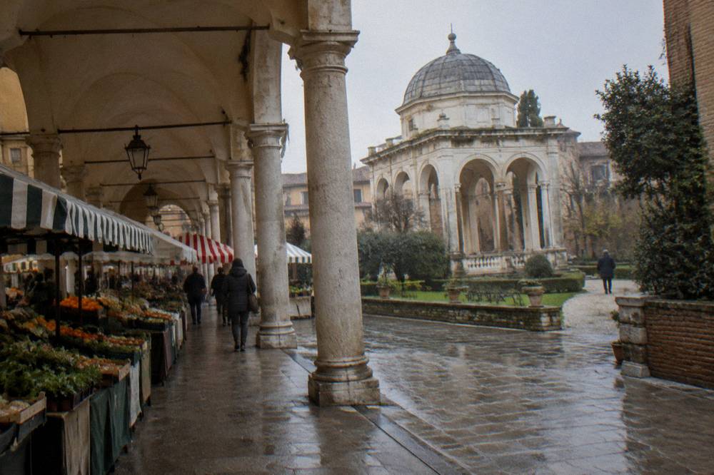 A covered loggia with striped market stalls in an old Italian square