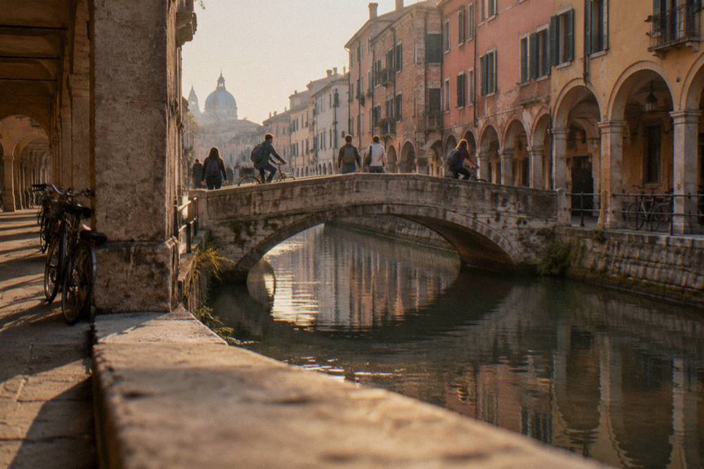 Students and cyclists crossing a small bridge over a canal in Padua