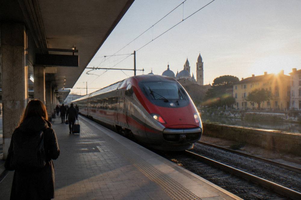 A train platform with a high speed train stopping at Padua station