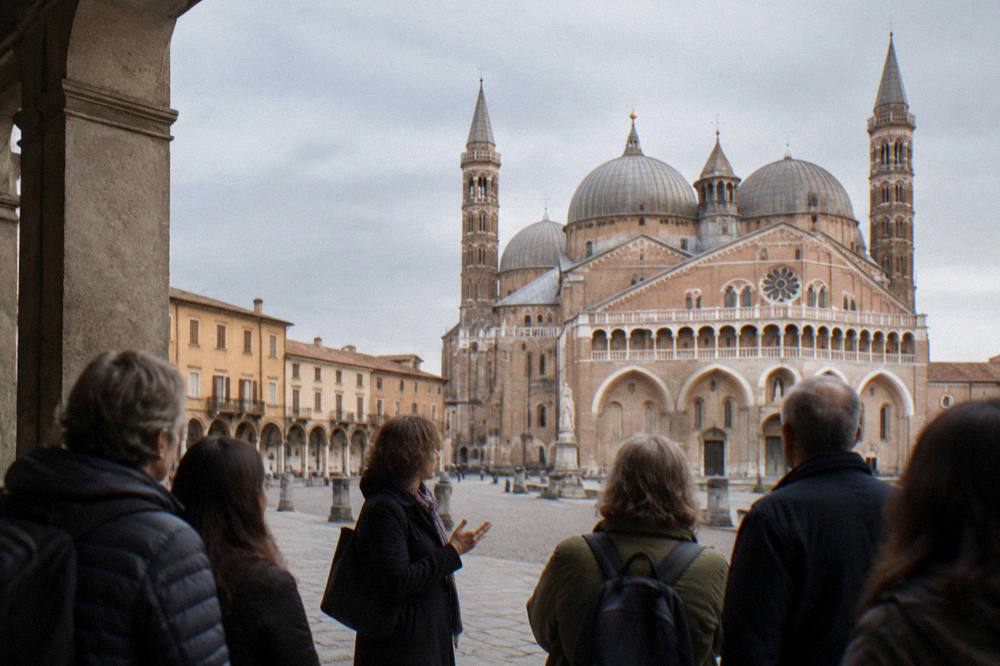 A small guided walking group listening to a guide beside the Basilica of Saint Anthony in Padua