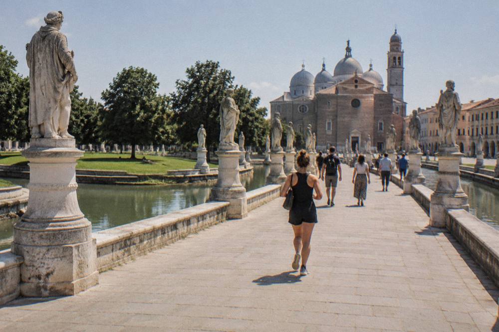 Visitors walking across the bridges of Prato della Valle toward the Basilica of Santa Giustina in Padua