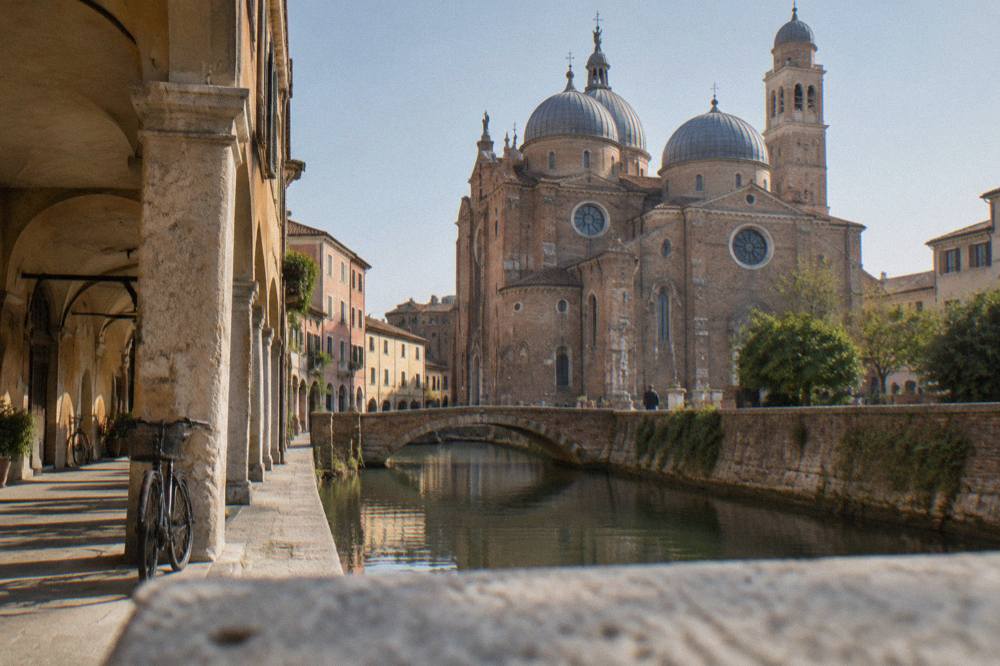The brick facade and domes of a large Padua abbey church under a clear sky