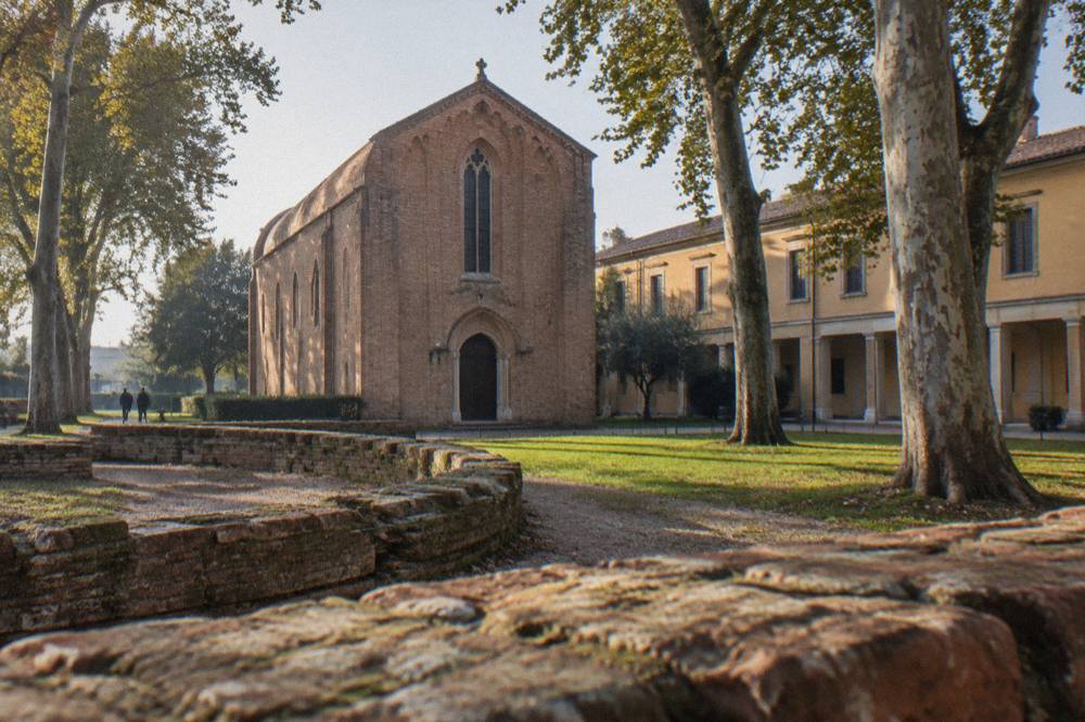 Exterior brick facade of a small gothic chapel beside a garden and museum buildings