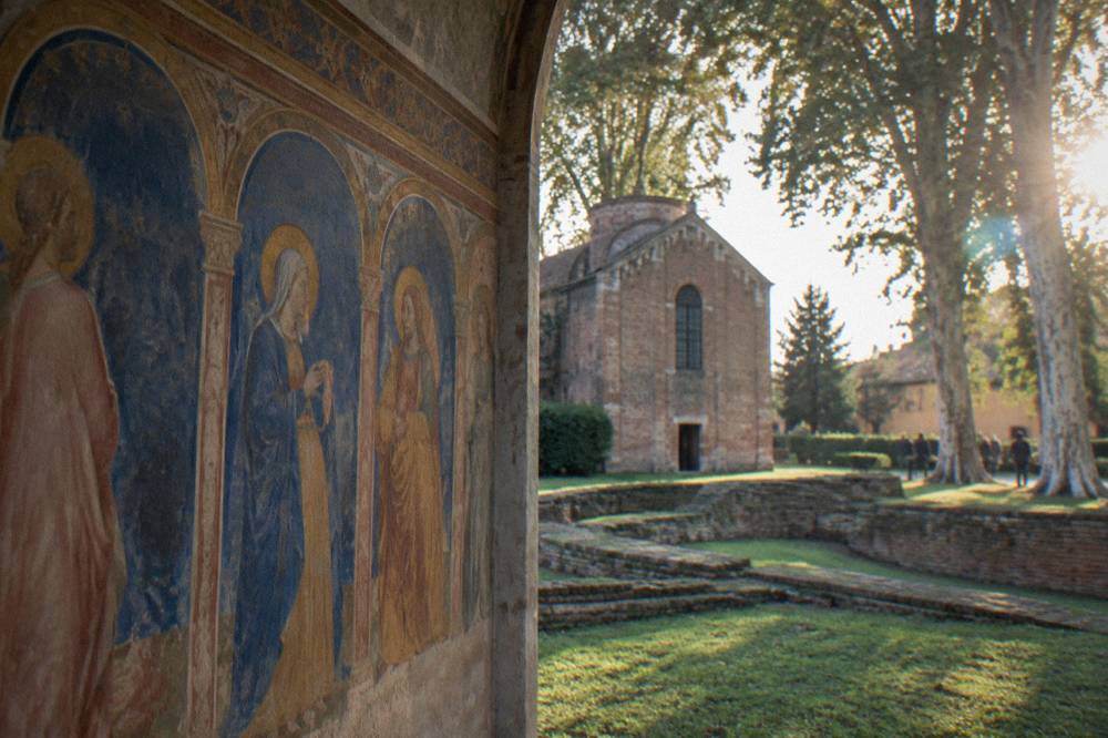 Close view of a frescoed scene showing robed figures under painted arches in blue and gold