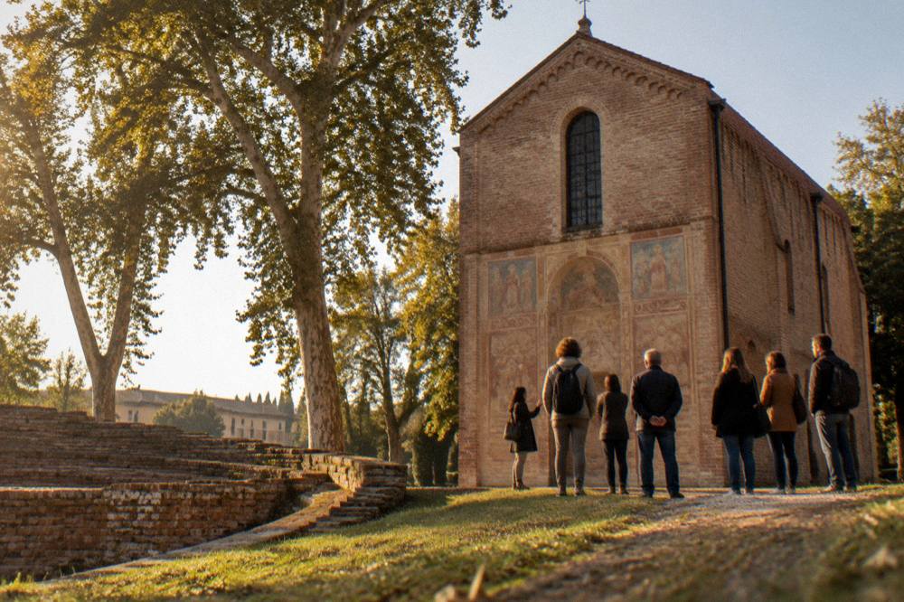 Small group of people with a guide standing before a frescoed chapel wall listening to an explanation