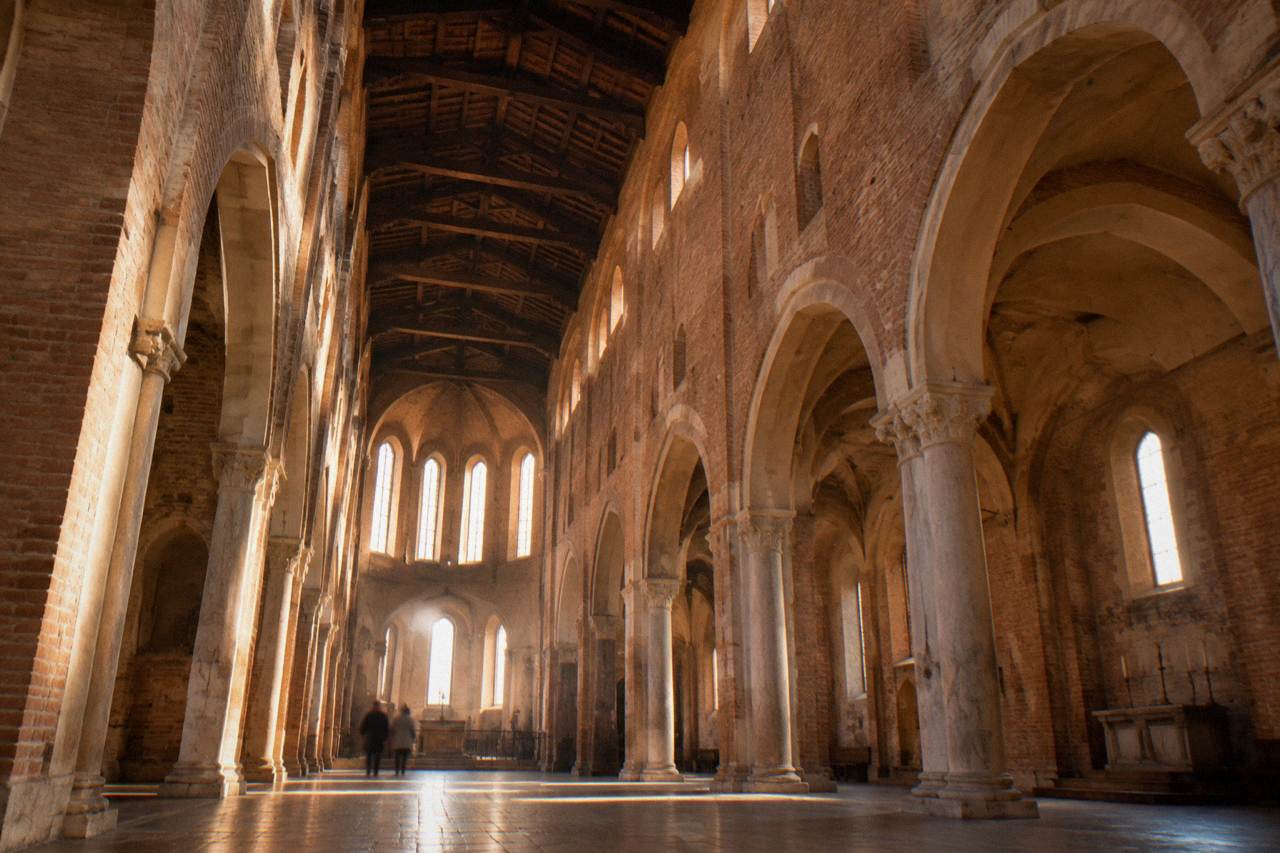 The brick Gothic interior of the Eremitani Church in Padua with its wooden beamed ceiling and open chapel arches