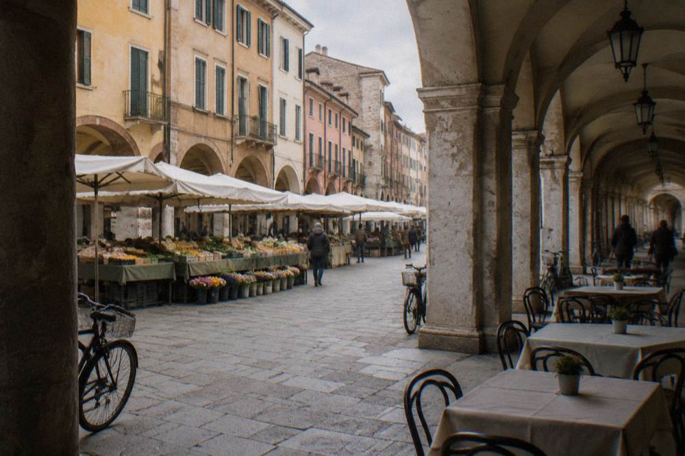 An arcaded street in central Padua with market stalls and cafe tables