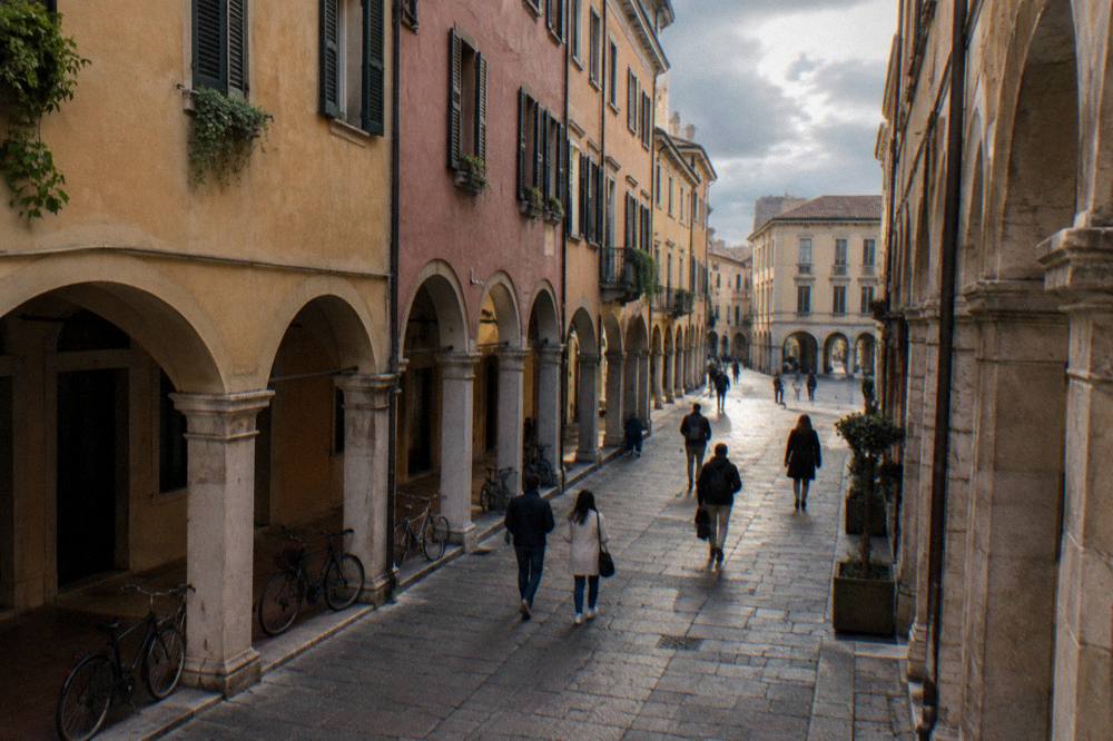 Visitors walking through an arcaded Padua street on a cloudy day