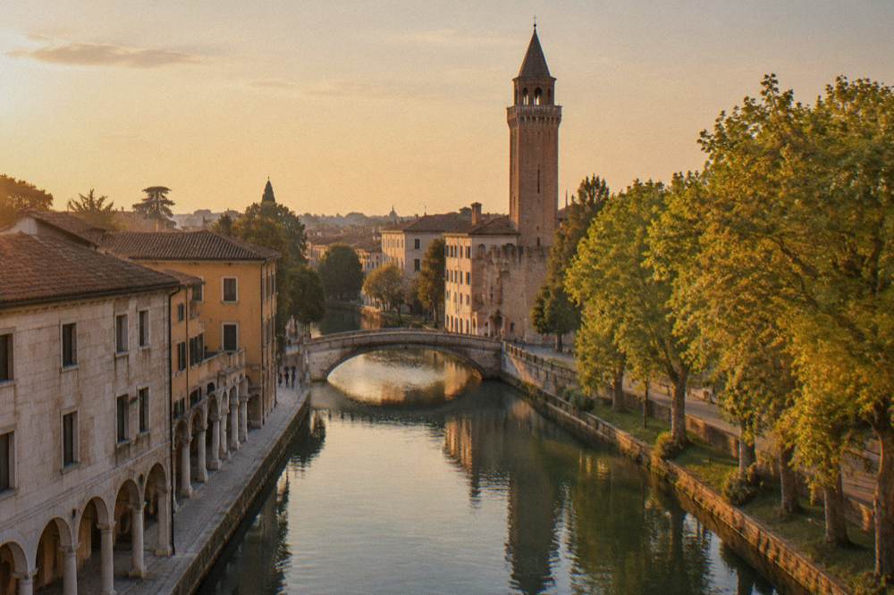 A view along a canal toward a stone bridge with the tower rising above rooftops