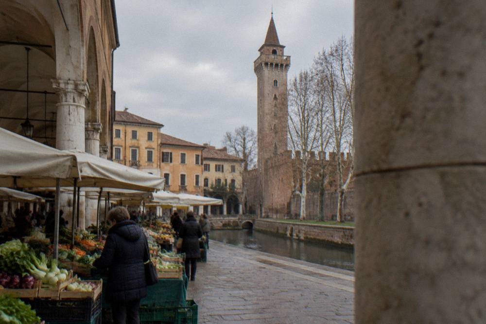 Market stalls with vegetables under the arcades of an old Italian square