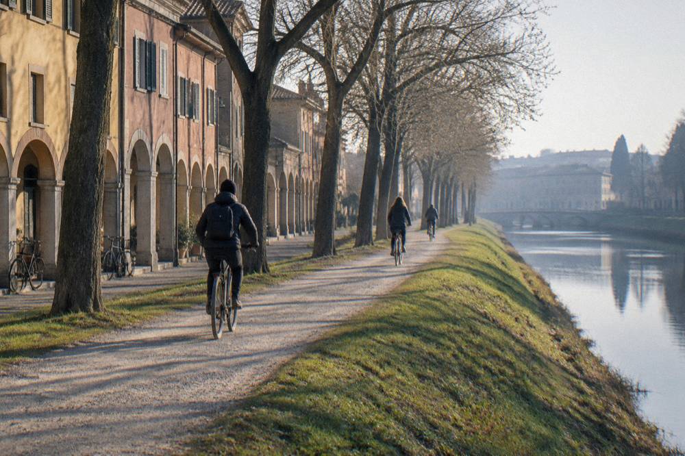 A tree-lined grass rampart path following the old walls of Padua with cyclists