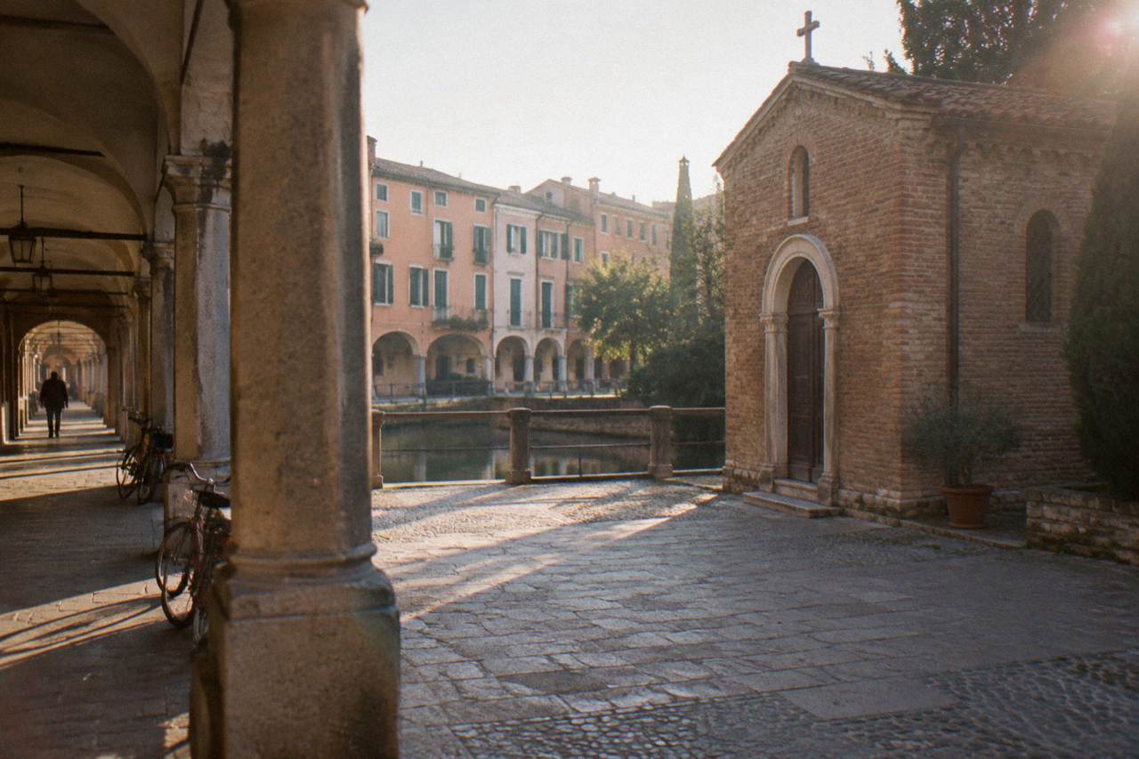 A small brick chapel exterior beside a cloister walkway in Padua