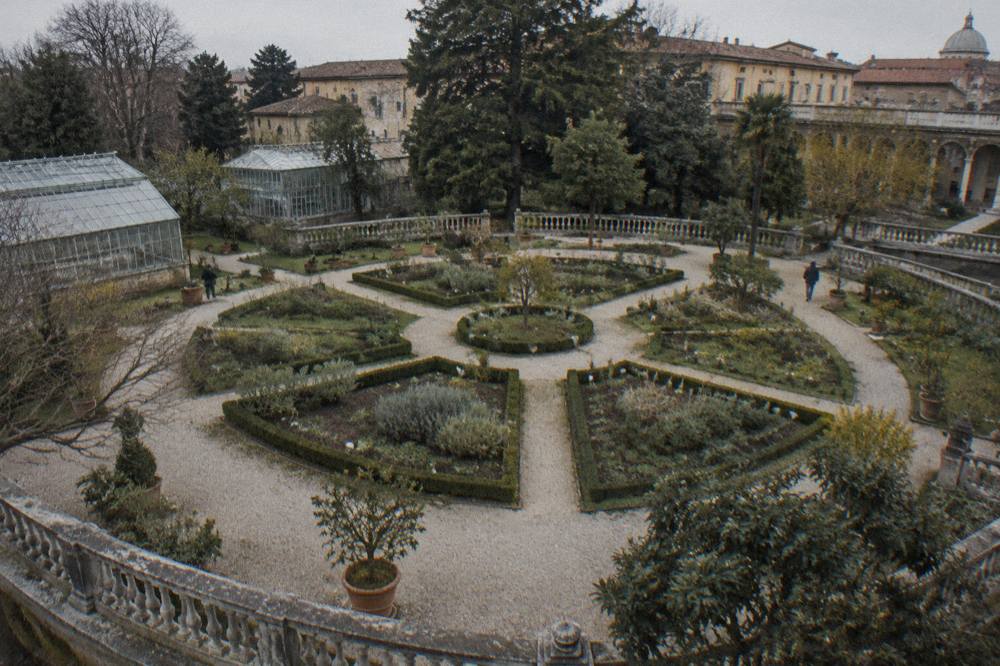 A circular garden plot divided into geometric beds with low hedges and labelled plants