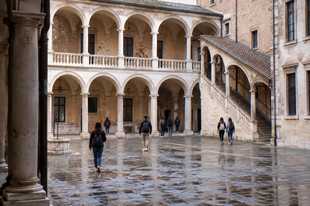 Students walking through an arched university courtyard in Padua