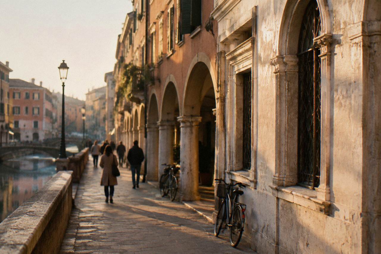 A historic Italian palace facade on a Padua street with arched windows and pedestrians passing below