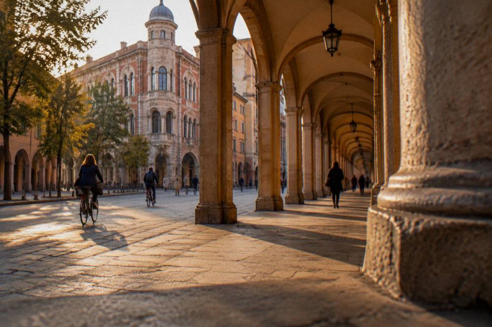 An arcaded Paduan street with cyclists and shoppers under medieval arches