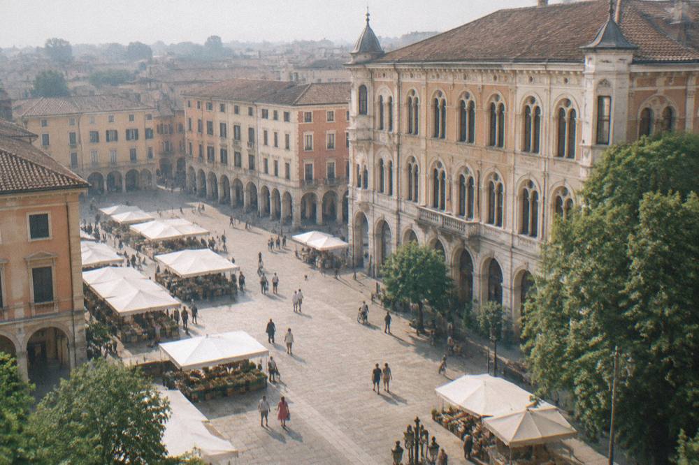 A wide Paduan square surrounded by historic buildings with a market and people strolling