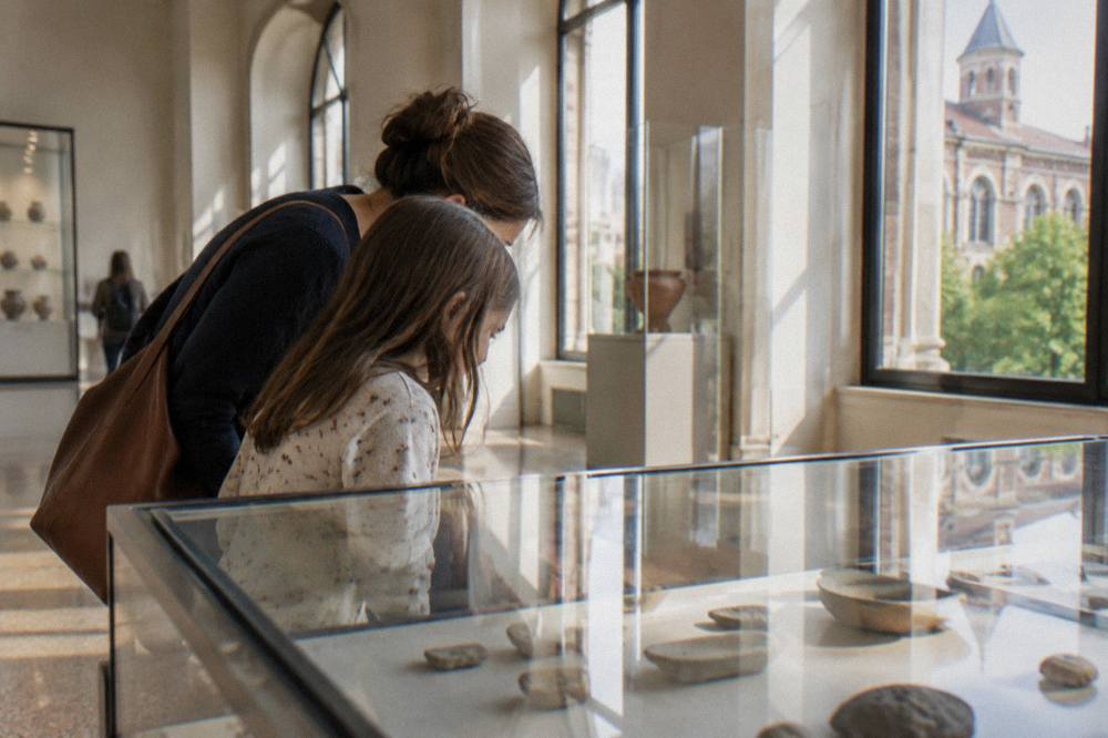 A child and adult looking into a glass museum case together in a bright gallery