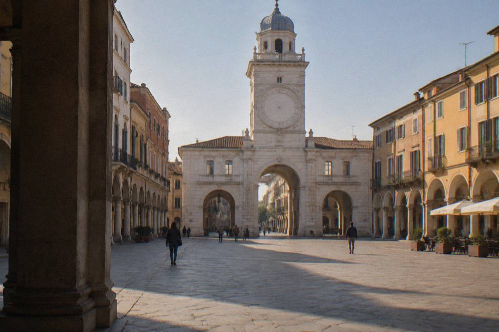 A wide Italian square with a clock tower archway and painted building facades