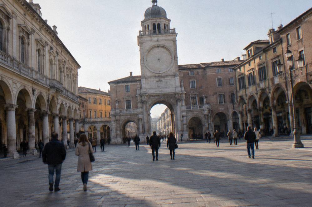 Tourists crossing a historic Italian square with arcades and a tall tower at one end