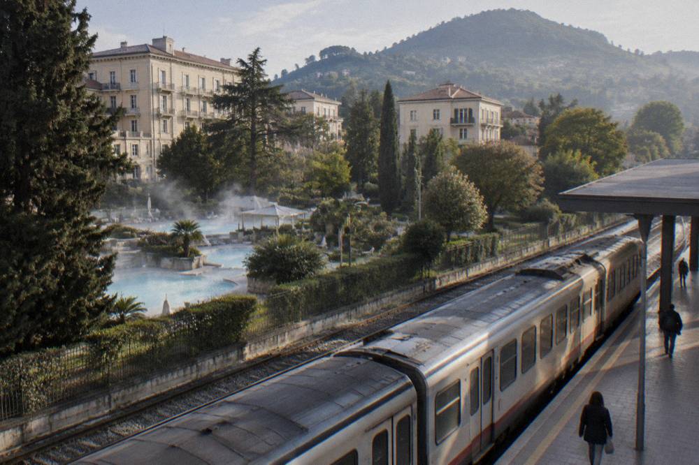 Train standing at a platform of an Italian railway station with departure boards