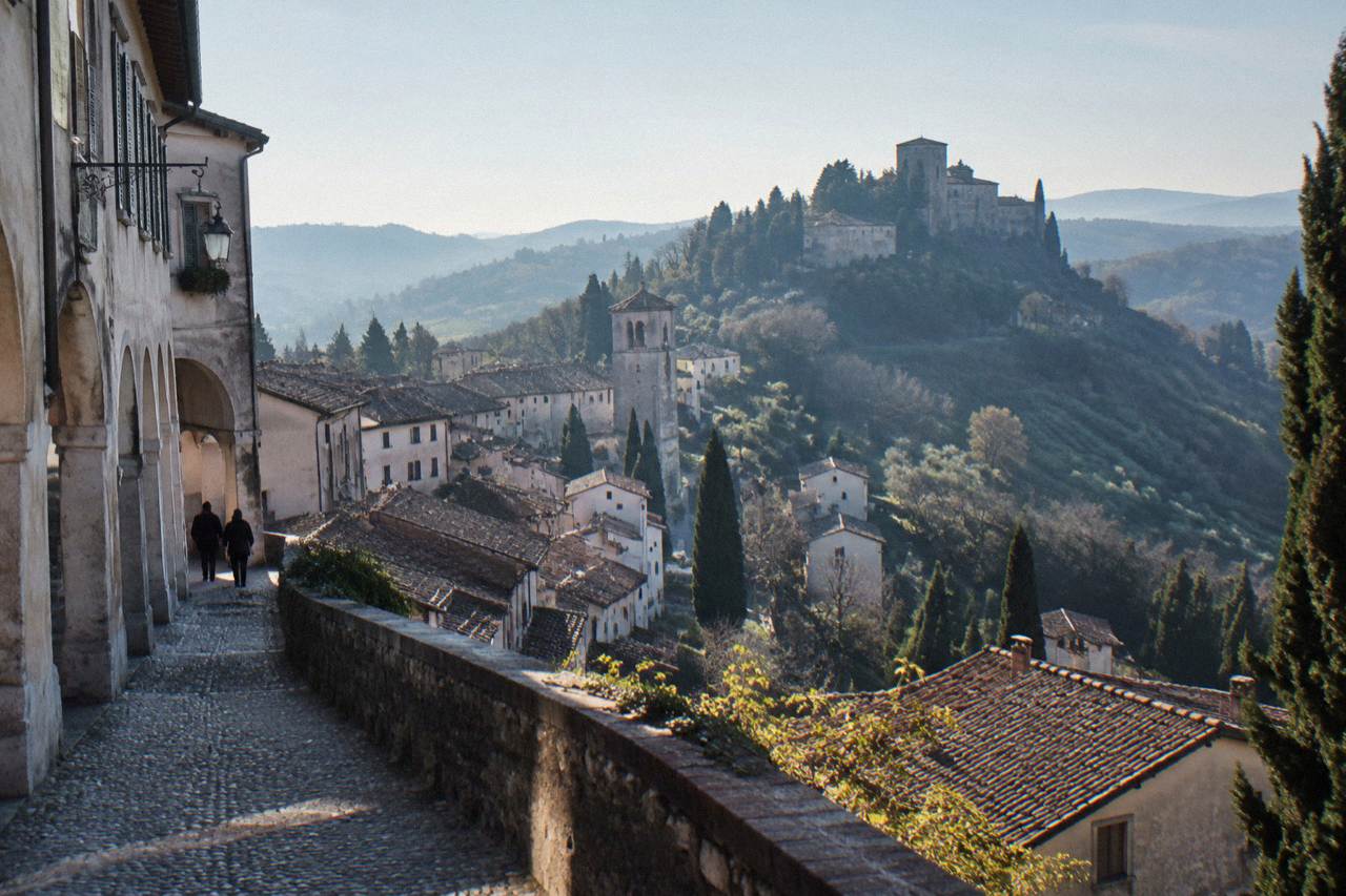 A stone hill town with terracotta roofs clustered beneath a fortified ridge in the Veneto countryside