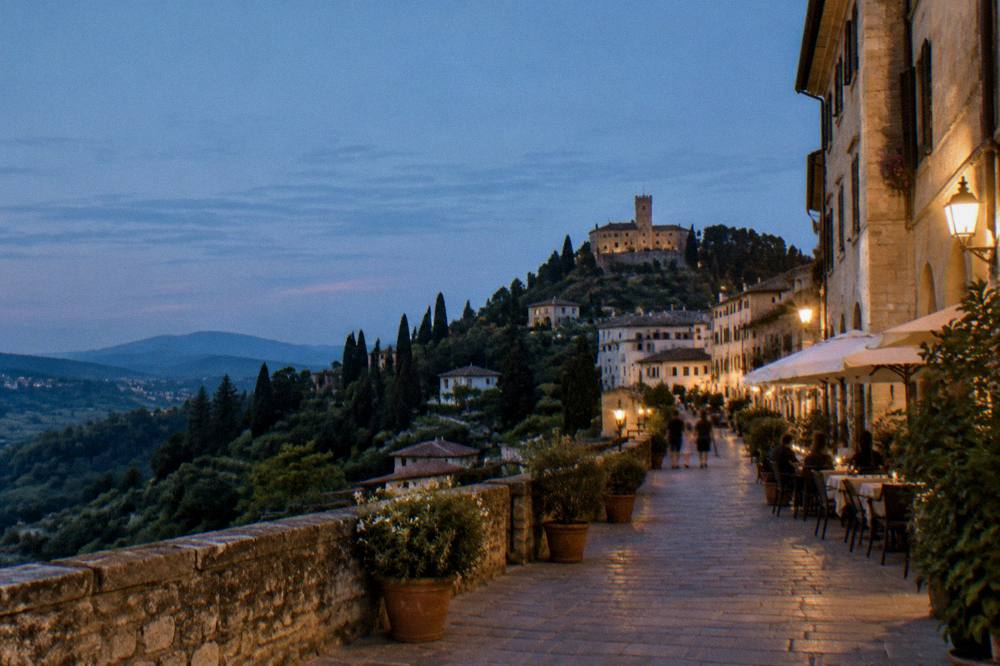 An evening street in a small Veneto town with warm light on stone facades and outdoor tables