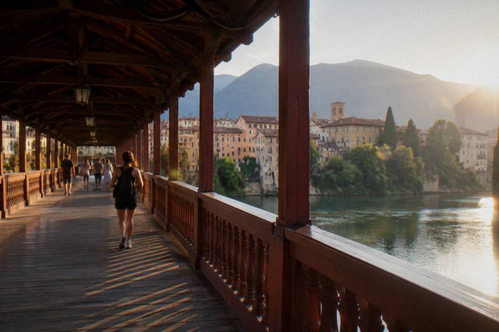 People strolling across a covered wooden bridge on a sunny afternoon