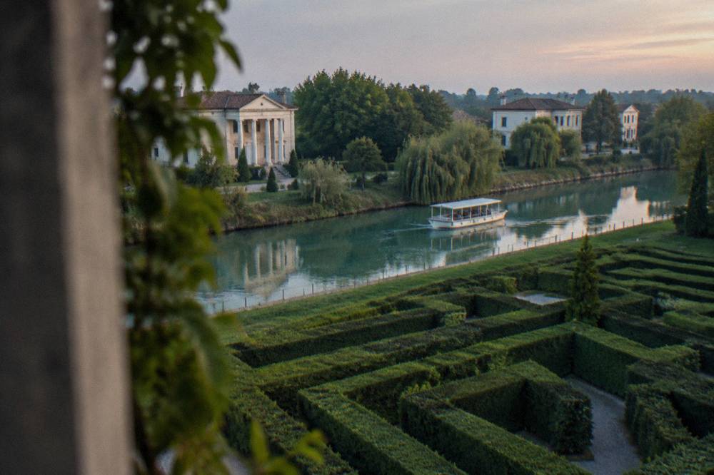 A symmetrical hedge maze seen from above with gravel paths between green walls