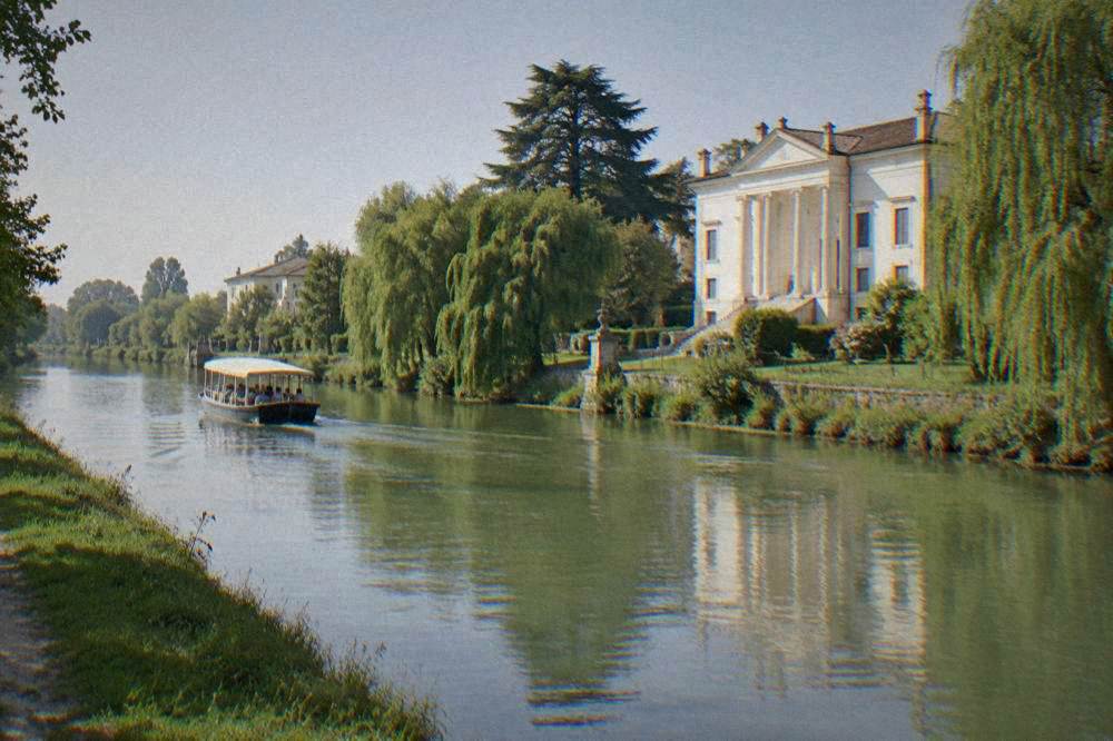 Quiet canal with a pale villa facade among trees