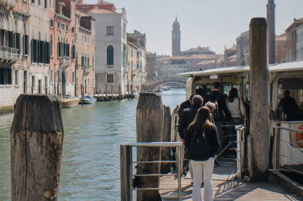 Travellers boarding a public ferry at a wooden landing stage in the Venice lagoon