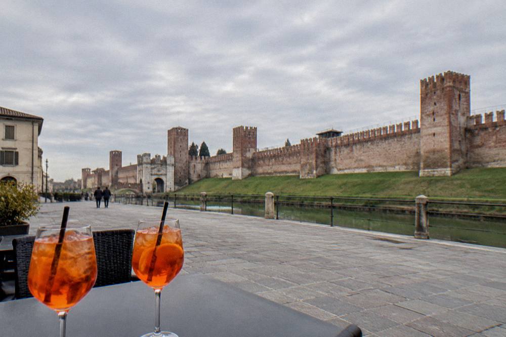 Two glasses of spritz on a table in a small Italian square