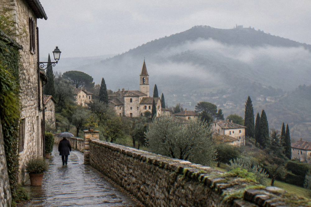 Morning mist over rounded wooded hills with a village spire below