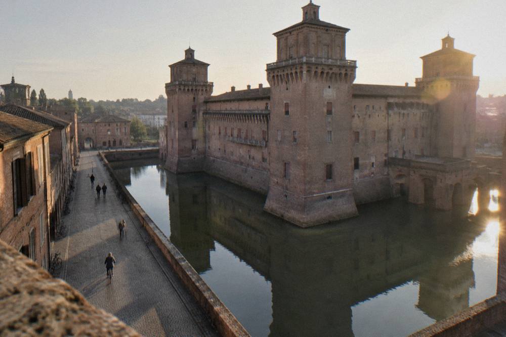 A stone castle keep rising above a water-filled moat in a city centre