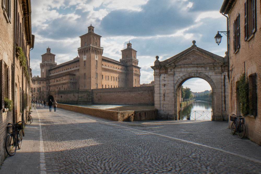 An old stone city gate with an archway opening onto a canal