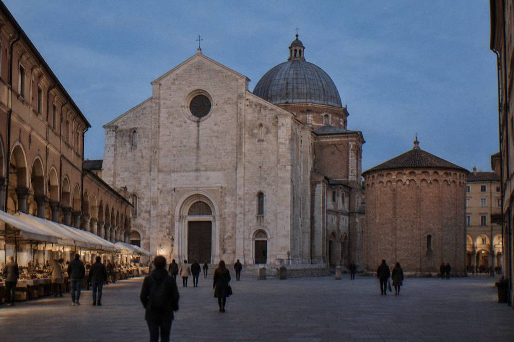 A medieval square with a cathedral facade and market stalls under arcades